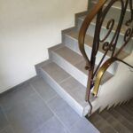 Pose de carrelage sur escalier intérieur et palier à Gomené (22), réalisée par Yann JEGOUZO, artisan carreleur à Saint-Méen-le-Grand (35290), Ille-et-Vilaine, Bretagne. Carrelage gris effet pierre avec finitions soignées pour la rénovation d'un escalier.
