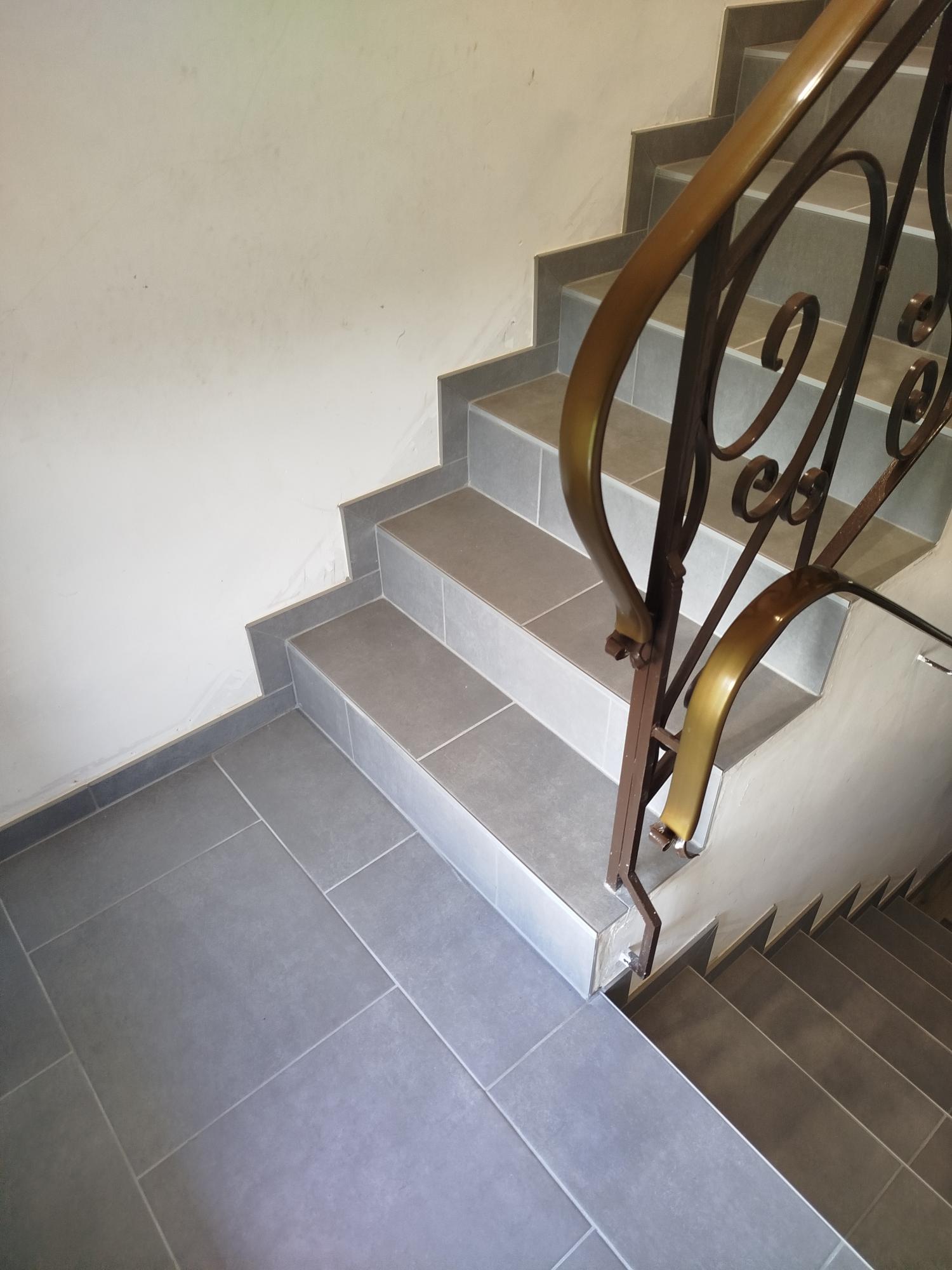 Pose de carrelage sur escalier intérieur et palier à Gomené (22), réalisée par Yann JEGOUZO, artisan carreleur à Saint-Méen-le-Grand (35290), Ille-et-Vilaine, Bretagne. Carrelage gris effet pierre avec finitions soignées pour la rénovation d'un escalier.
